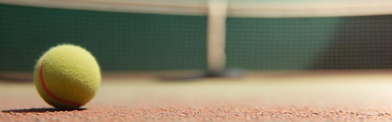 Vue rapprochée d'une balle de tennis sur la ligne de fond d'un court.