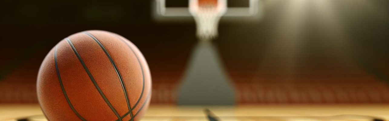 Un ballon de basket au centre d'un terrain en bois sous une lumière naturelle.