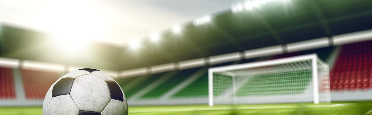 Un ballon de football use repose sur une pelouse verte dans un stade.