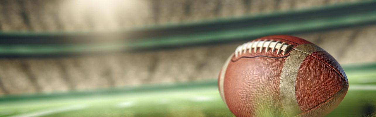 Un ballon de football use repose sur une pelouse verte dans un stade vide.