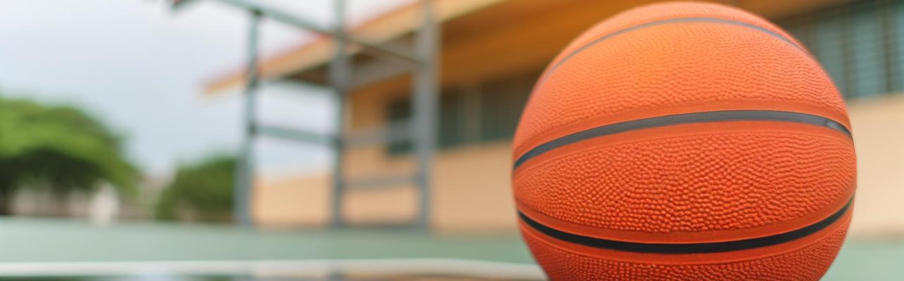 Un ballon de basketball sur un terrain exterieur mouille, avec un panier en arriere-plan.
