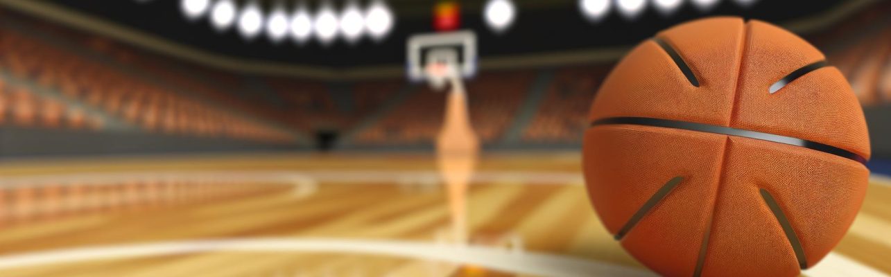 Un ballon de basketball repose sur le terrain avec des paniers flous en arrière-plan.