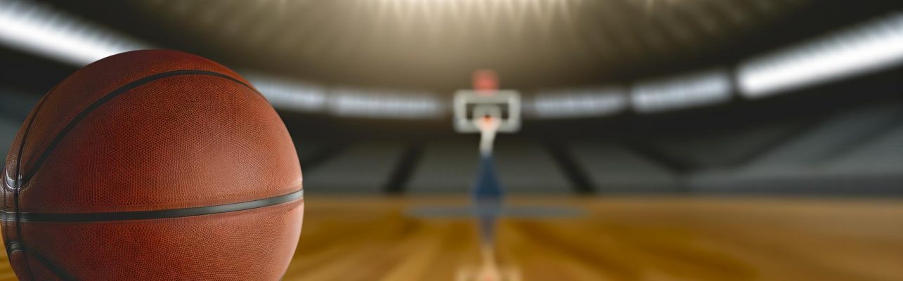 Un ballon de basketball sur un terrain en bois avec des ombres douces et un stade vide en arrière-plan.