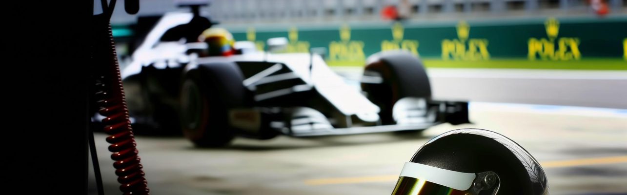 Casque de course de Formule 1 sur un mur de stand avec le circuit en arrière-plan.