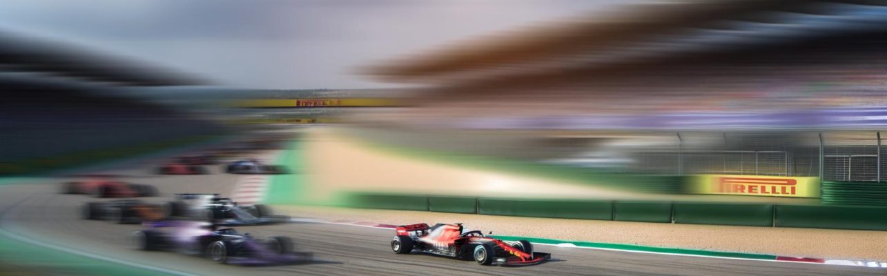 Une piste de course de Formule 1 pendant un événement diurne, avec des voitures de course aux lignes élégantes et colorées.