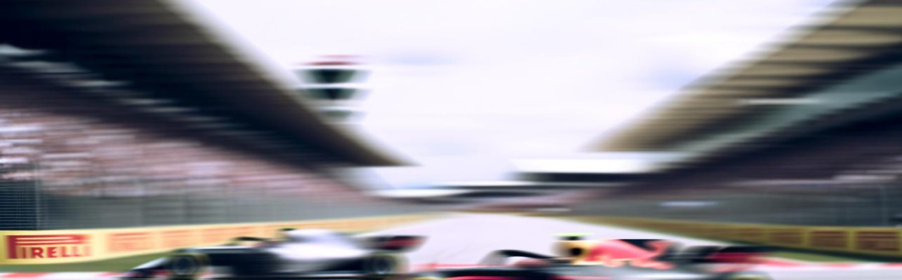 Photo de voitures de Formule 1 sur un circuit avec des spectateurs en arrière-plan flou.