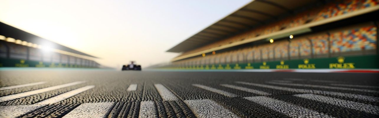 Un circuit de Formule 1 à l'aube avec une grille de départ vide, des détails de l'asphalte et des marquages visibles.