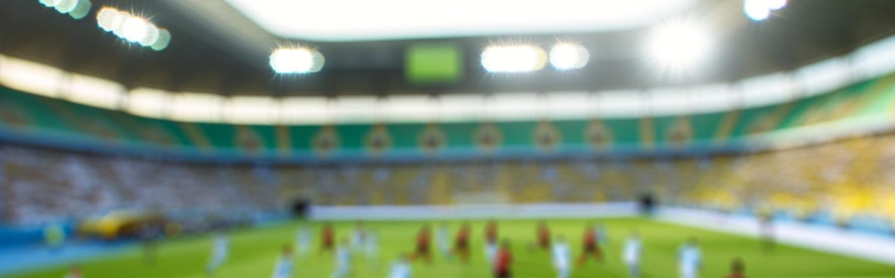 Un stade de football pendant un match en plein jour avec des joueurs en mouvement.