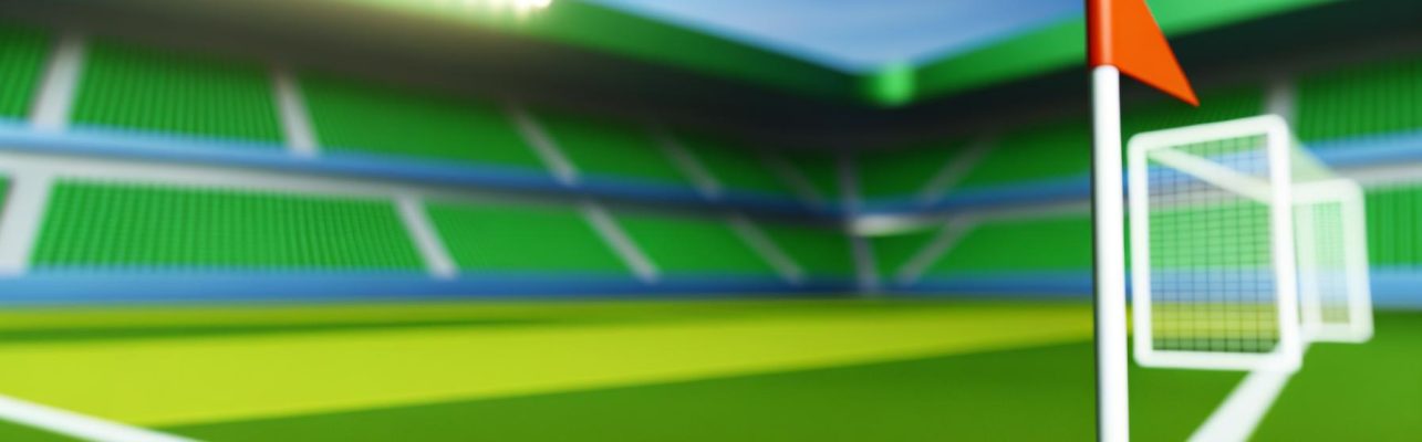 Un terrain de football avec des buts blancs au loin et un drapeau de coin au premier plan.