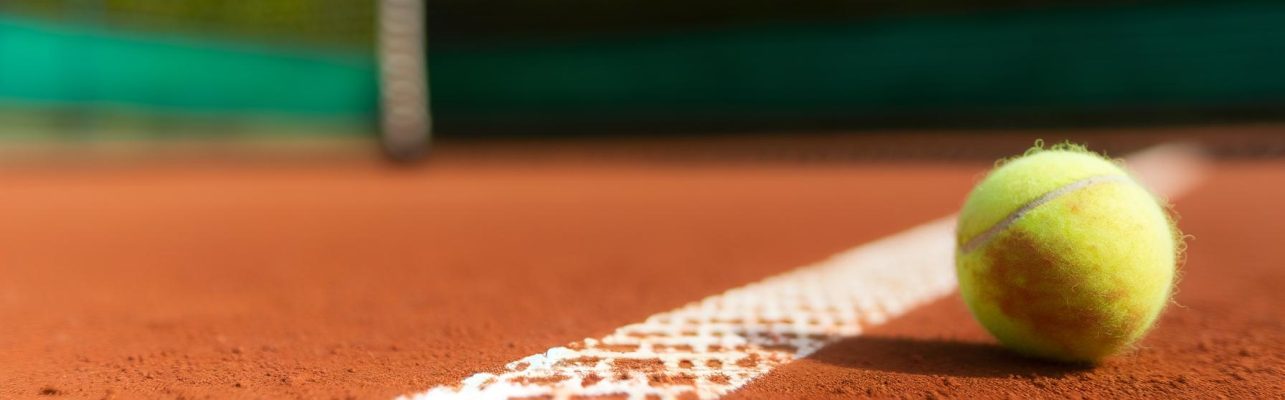 Un court de tennis en gros plan avec une balle sur la terre battue.