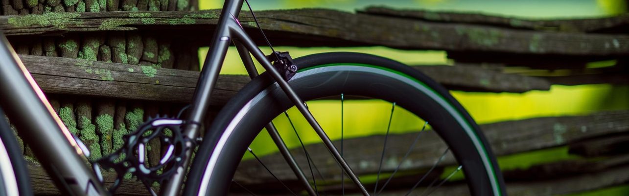 Un gros plan d'un vélo de route haut de gamme appuyé contre une clôture en bois rustique dans un cadre naturel.