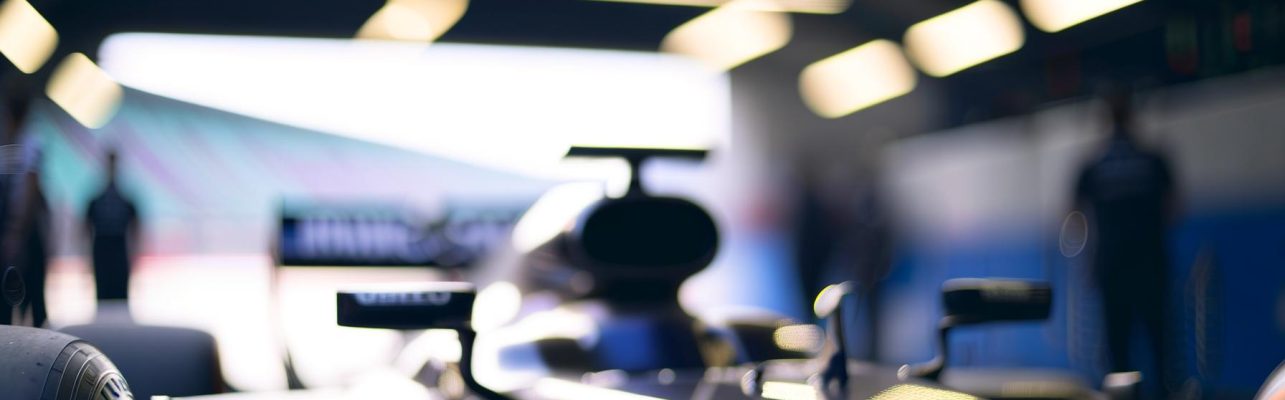 Voiture de course de Formule 1 dans l'allée des stands avec un design aérodynamique et des logos visibles.