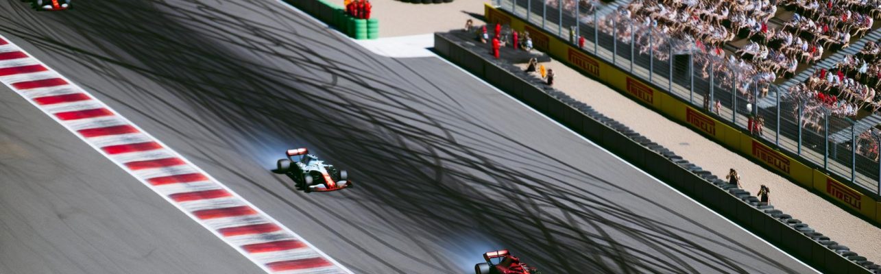 Vue aérienne d'un circuit de Formule 1 avec des voitures en mouvement et des tribunes remplies de spectateurs.